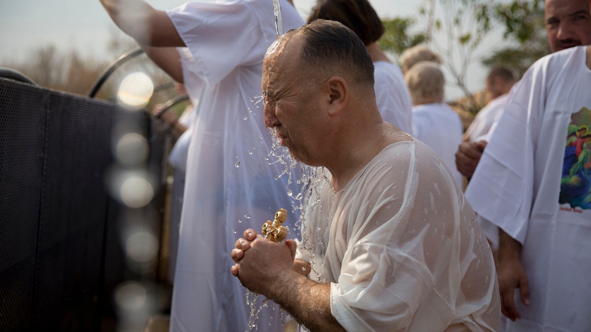 A Christian pilgrim takes part in baptism in the Jordan river during the Orthodox Feast of the Epiphany at Qasr el Yahud, Saturday, Jan. 18, 2020. (AP Photo/Majdi Mohammed)