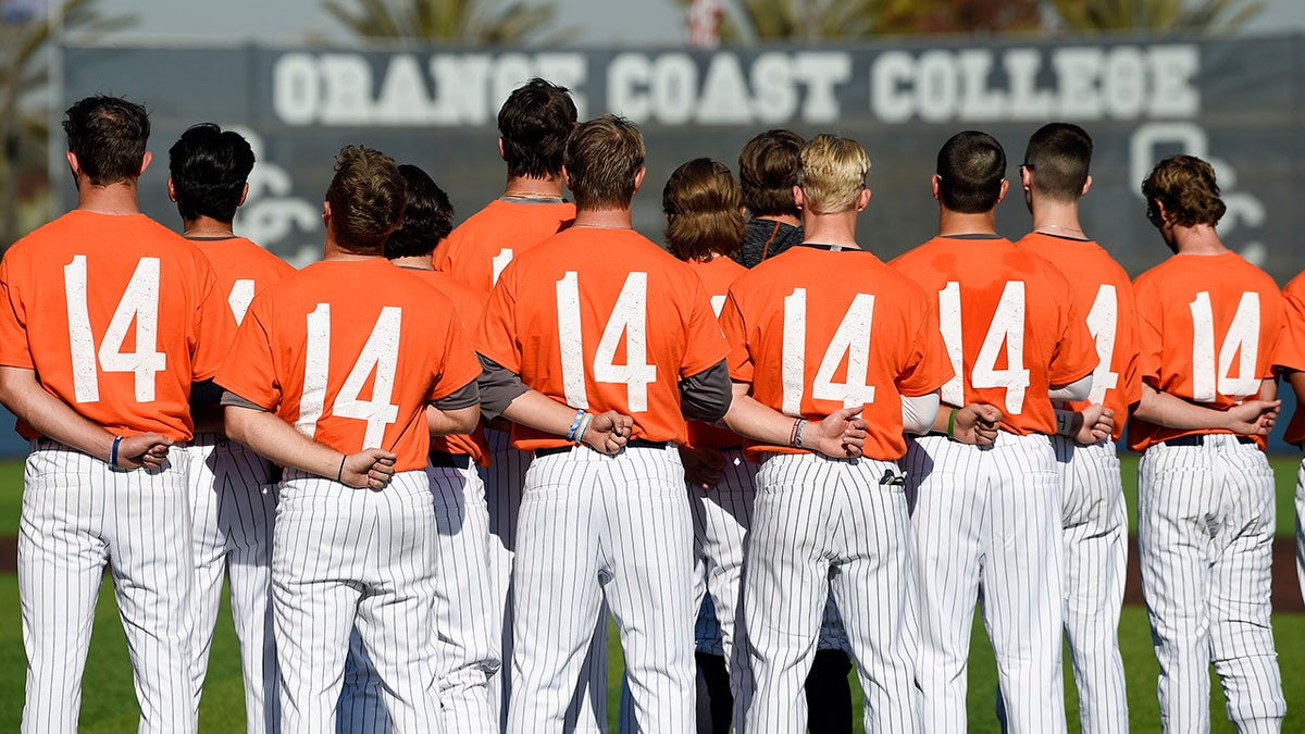 The Orange Coast College baseball players stands for the national anthem while wearing shirts with the number 14 on their backs for late head coach John Altobelli, who died in a helicopter crash alongside former NBA basketball player Kobe Bryant in Costa Mesa, Calif., Tuesday, Jan. 28, 2020. (AP Photo/Kelvin Kuo)