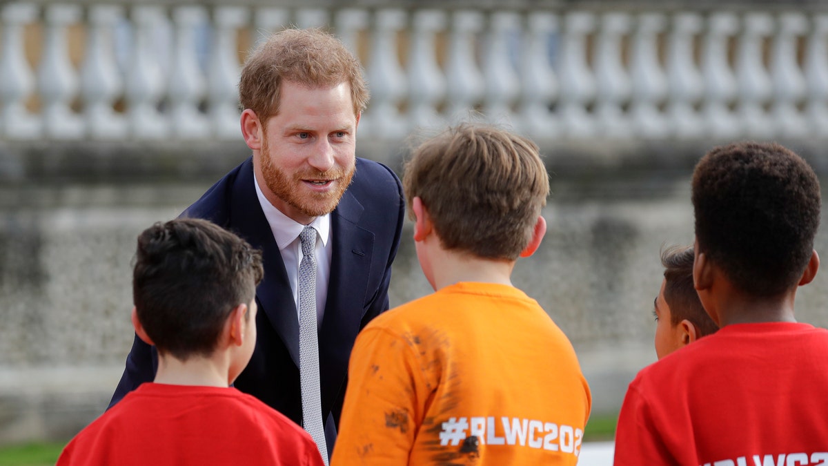 Britain's Prince Harry greets schoolchildren in the gardens at Buckingham Palace in London, Thursday, Jan. 16, 2020. Prince Harry, the Duke of Sussex will host the Rugby League World Cup 2021 draw at Buckingham Palace, prior to the draw, The Duke met with representatives from all 21 nations taking part in the tournament, as well as watching children from a local school play rugby league in the Buckingham Palace gardens. (AP Photo/Kirsty Wigglesworth)