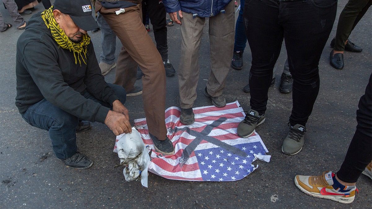 Mourners step over a U.S. flags before burning it during the funeral of Iran's top general Qassem Soleimani and Abu Mahdi al-Muhandis, deputy commander of Iran-backed militias in Iraq known as the Popular Mobilization Forces, in Baghdad, Iraq, Saturday, Jan. 4, 2020. Thousands of mourners chanting "America is the Great Satan" marched in a funeral procession Saturday through Baghdad for Iran's top general and Iraqi militant leaders, who were killed in a U.S. airstrike. (AP Photo/Nasser Nasser)