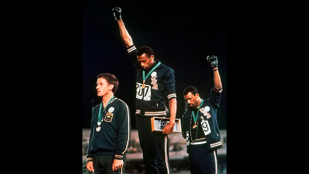 U.S. athletes Tommie Smith, center, and John Carlos, right, raise their gloved fists after Smith received the gold and Carlos the bronze for the 200 meter run at the Summer Olympic Games in Mexico City, Oct. 16, 1968. (Associated Press)