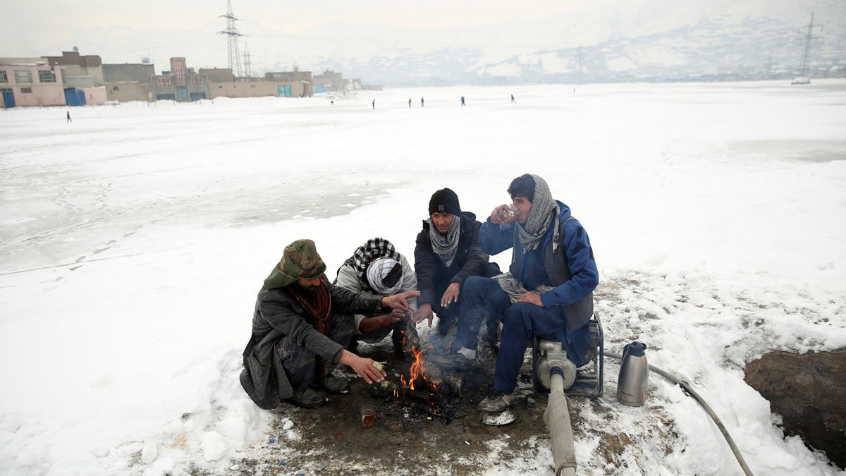 People sit around a fire to warm themselves after a heavy snowfall in Kabul, Afghanistan, Tuesday, Jan. 14, 2020.