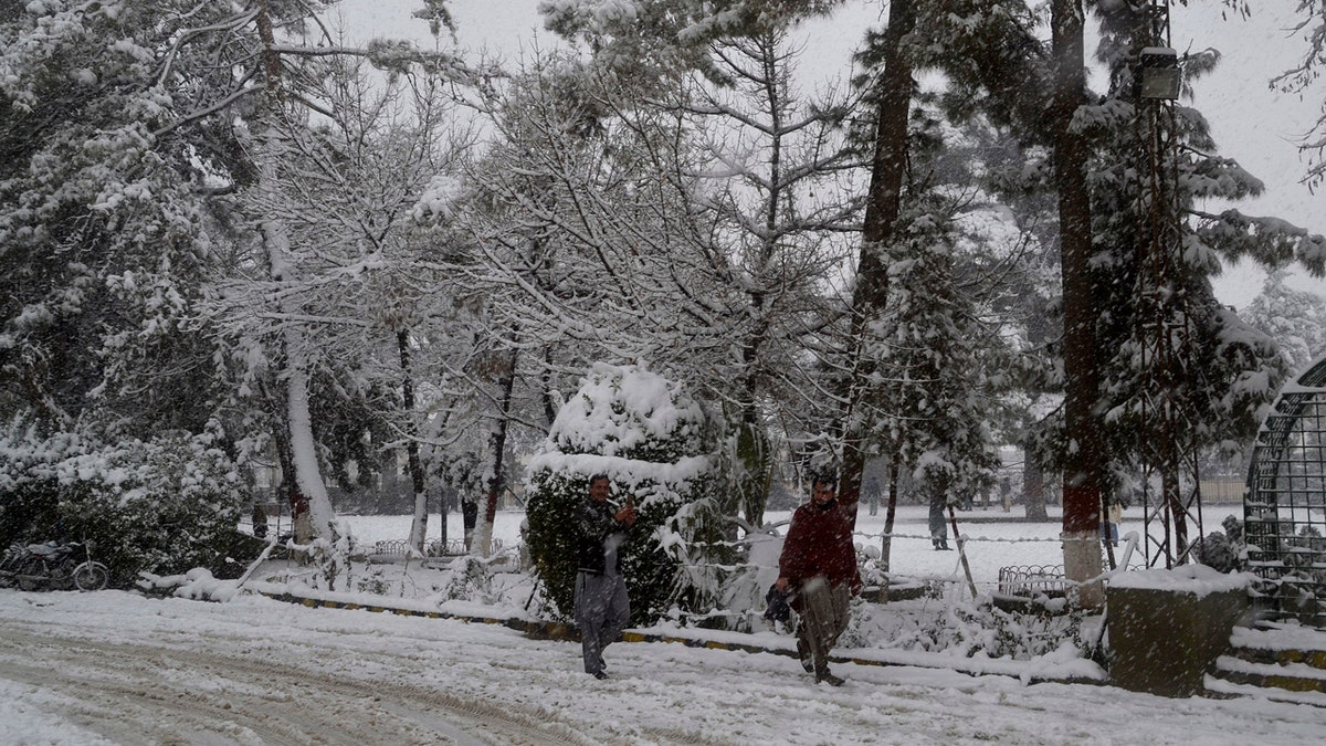 In this Sunday, Jan. 12, 2020, photo, people walk on a road during heavy snow fall in Quetta, capital of Pakistan's southwestern Baluchistan province.
