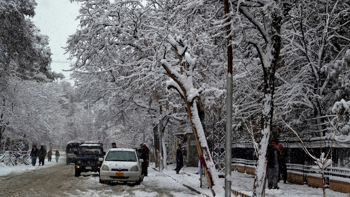 In this Sunday, Jan. 12, 2020, photo, people walk on a road during heavy snow fall in Quetta, capital of Pakistan's southwestern Baluchistan province.