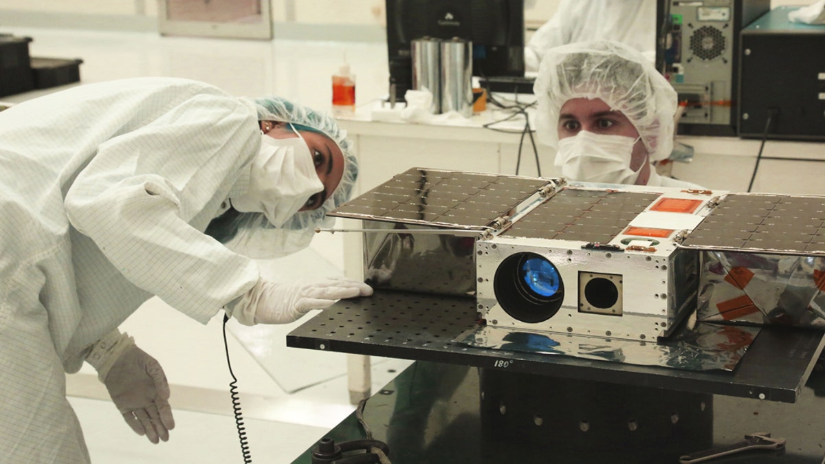 Left to right: Electrical Test Engineer Esha Murty and Integration and Test Lead Cody Colley prepare the ASTERIA spacecraft for mass-properties measurements in April 2017 prior to spacecraft delivery ahead of launch. ASTERIA was deployed from the International Space Station in November 2017. Credit: NASA/JPL-Caltech