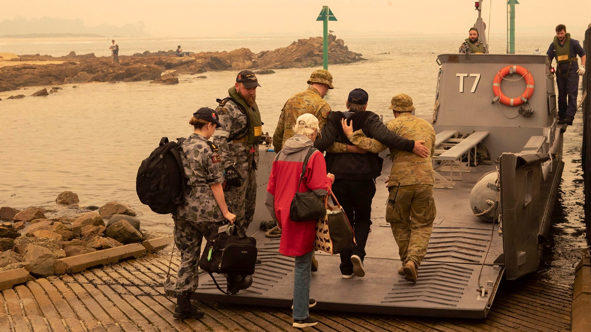 In this photo released by the Australian Department of Defense, evacuees board landing craft to be ferried out to the navy's HMAS Choules, Friday, Jan. 3, 2020, in Mallacoota, Victoria, Australia.