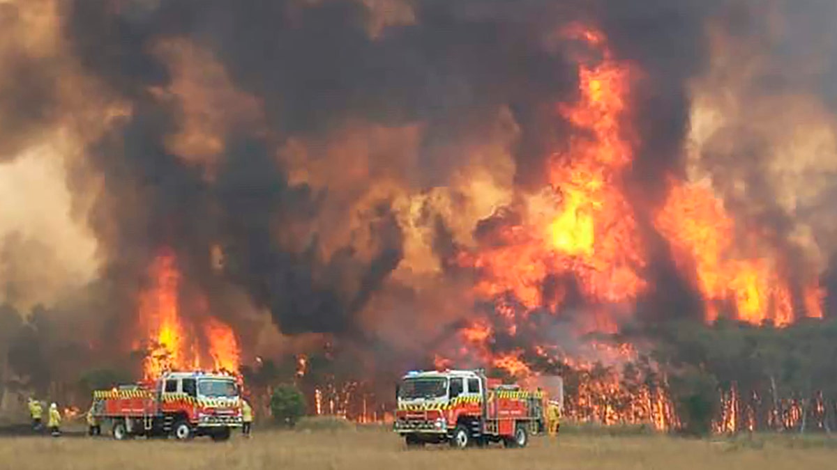 In this image dated Dec. 30, 2019, and provided by NSW Rural Fire Service via their twitter account, firefighters are seen as they try to protect homes around Charmhaven, New South Wales.? (Twitter@NSWRFS via AP)