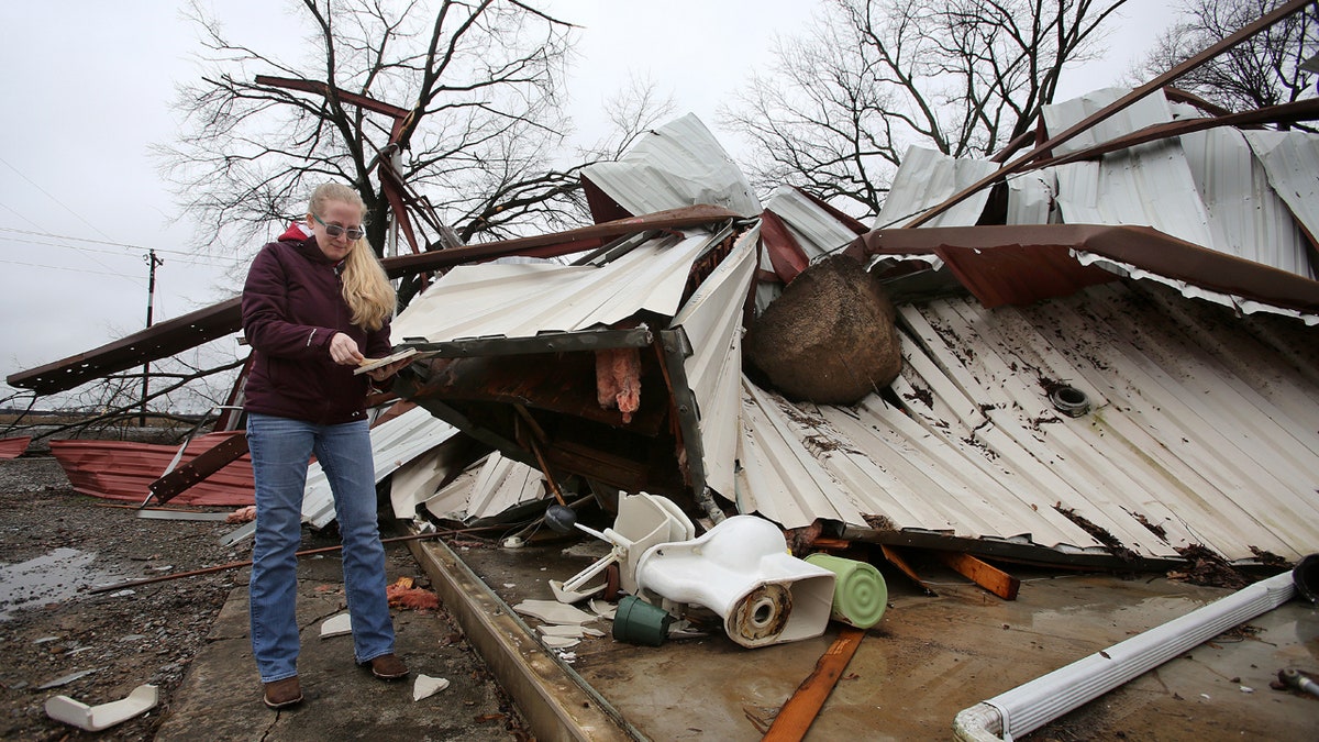 Scarlett Faulk looks at a Bible belonging to one of her brothers that she pulled out of from a destroyed building on her family's land on Saturday, Jan. 11, 2020, in southern Lonoke County, Ark.