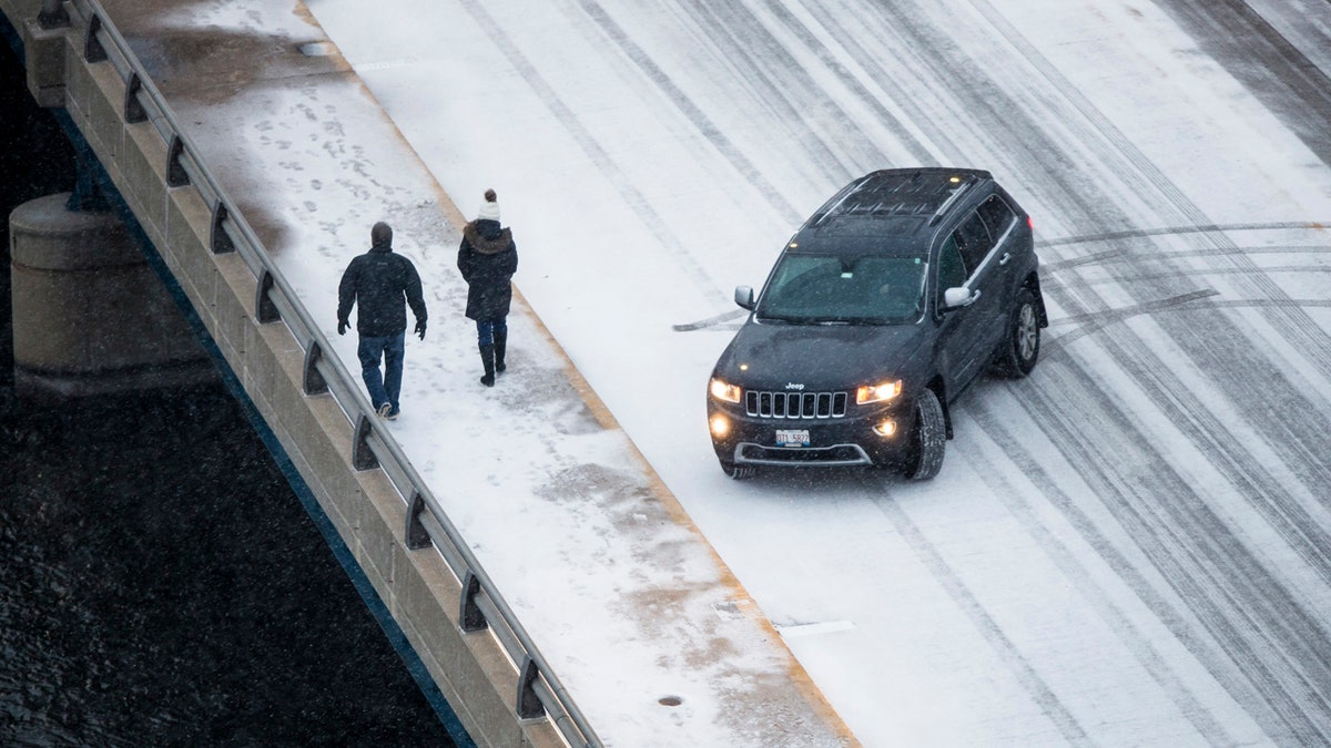 Snow accumulates as pedestrians walk on East State Street, on Saturday, Jan. 11, 2020, in Rockford, Ill.