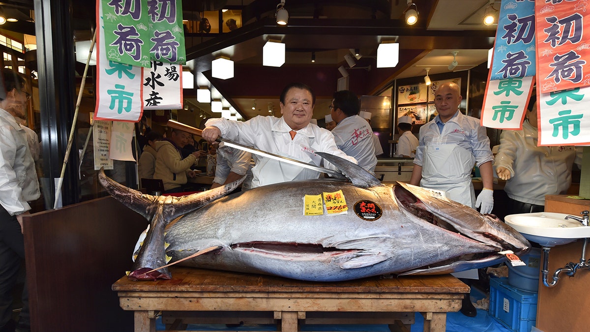 Kiyoshi Kimura (C), president of Kiyomura Corp., the Tokyo-based operator of sushi restaurant chain Sushizanmai, poses with a sword before slicing up a bluefin tuna the company bought for 193.2 million yen (1.8 million USD).