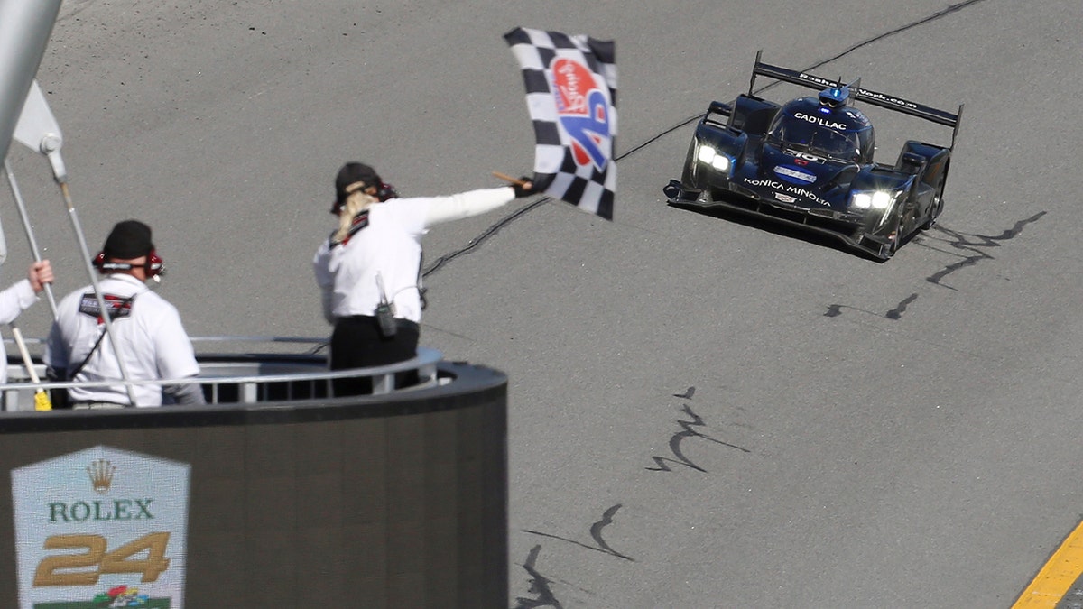 Konica Minolta Cadillac DPi-V.R driver Kamui Kobayashi takes the checkered flag to win the Rolex 24-hour auto race at Daytona International Speedway, Sunday, Jan. 26, 2020, in Daytona Beach, Fla. (AP Photo/David Graham)