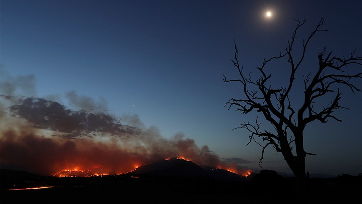 A wildfire threatening property glows at dusk near Clear Range, south of the Australian capital of Canberra on Friday.