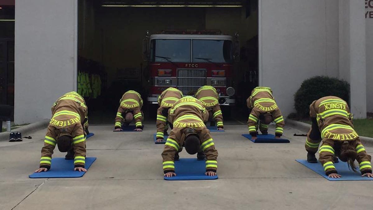 Firefighters in a downward dog pose.