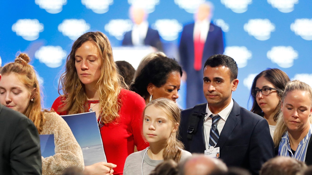 Swedish environmental activist Greta Thunberg, center, leaves as U.S. President Donald Trump, rear right, and Executive Chairman Klaus Schwab, rear left, are seen at the World Economic Forum in Davos, Switzerland, Tuesday, Jan. 21, 2020. The 50th annual meeting of the forum will take place in Davos from Jan. 21 until Jan. 24, 2020. (AP Photo/Markus Schreiber)