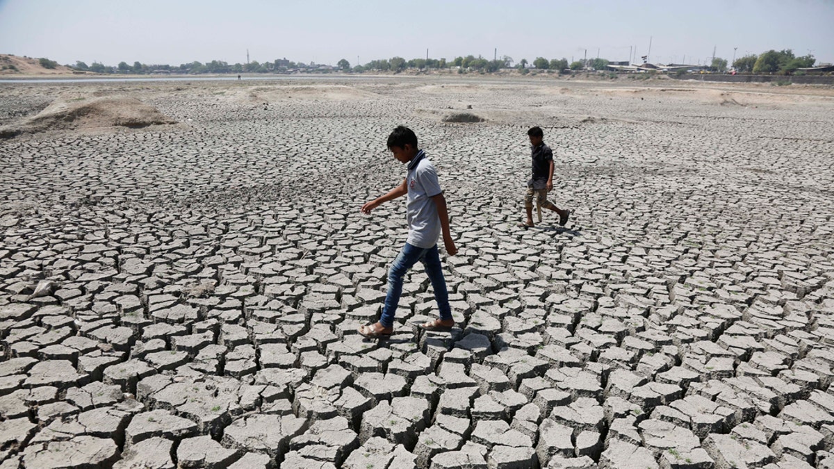 FILE - In this May 14, 2016, file photo, boys on their way to play cricket walk through a dried patch of Chandola Lake in Ahmadabad, India. The decade that just ended was by far the hottest ever measured on Earth, capped off by the second-warmest year on record, NASA and the National Oceanic and Atmospheric Administration reported Wednesday, Jan. 15, 2020. (AP Photo/Ajit Solanki, File)