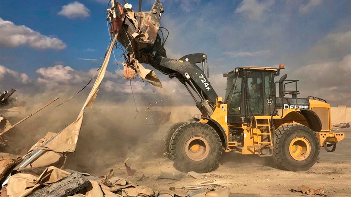 A bulldozer clears rubble and debris at the base. (AP)