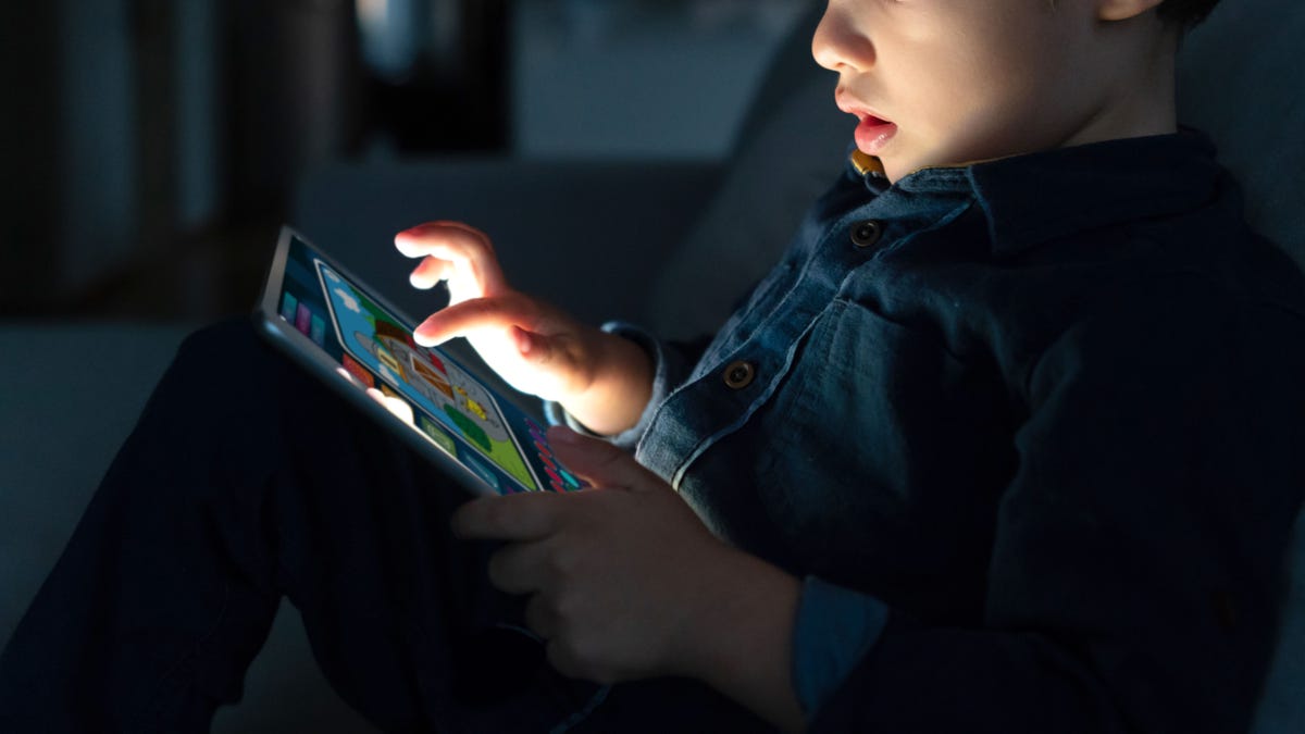 Young boy using a digital tablet at home at nighttime