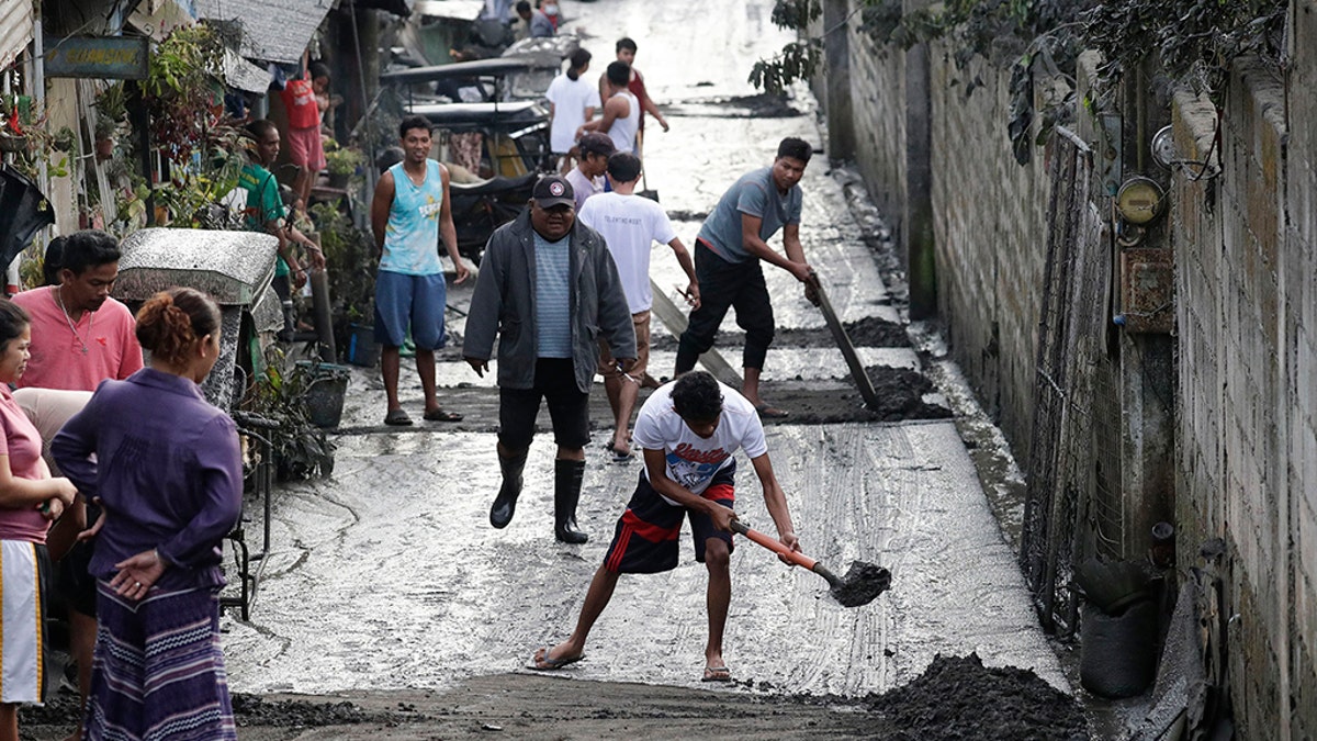 Residents clean ash outside their homes as Taal Volcano still spews ash on Monday Jan. 13, 2020, in Tagaytay, Cavite province, south of Manila, Philippines. (AP Photo/Aaron Favila)