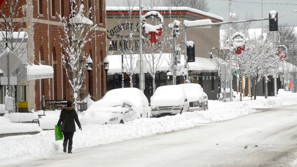 A pedestrian makes her way along a snow-covered Front Street in downtown Port Angeles, Wash., on Wednesday, Jan. 15, 2020, after heavy snow blanketed the city overnight.