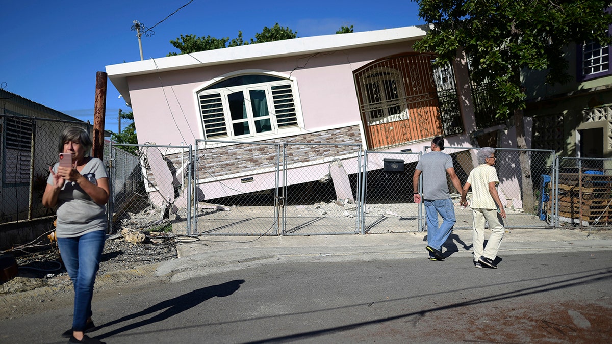 Residents surveyed damage where a home partially collapsed in Guanica on Monday. (AP Photo/Carlos Giusti)