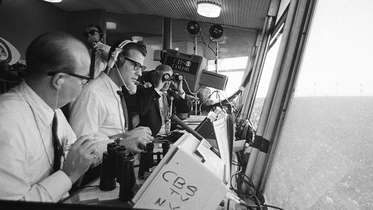 The first Super Bowl was played at the Memorial Coliseum in Los Angeles, Jan. 15, 1967. In foreground is announcer Ray Scott. Wearing headset is commentator Frank Gifford. In the background, holding binoculars, is Jack Whitaker. (Photo by CBS via Getty Images)