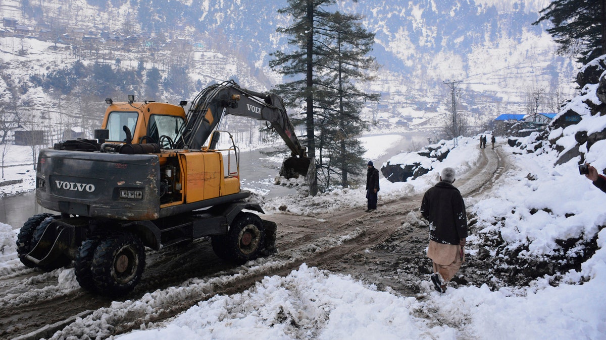 Workers with heavy machinery clear a snow-covered road in Keran, a small town in Neelum Valley, Pakistan-administered Kashmir, Tuesday, Jan. 14, 2020.