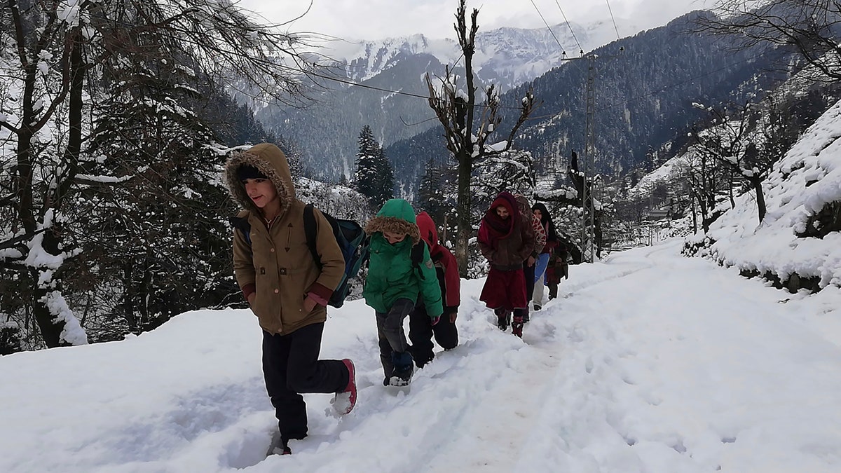 Kashmiri children walk through snow-covered road after heavy snowfall in Neelum Valley, Pakistan-administered Kashmir, Wednesday, Jan. 15, 2020.
