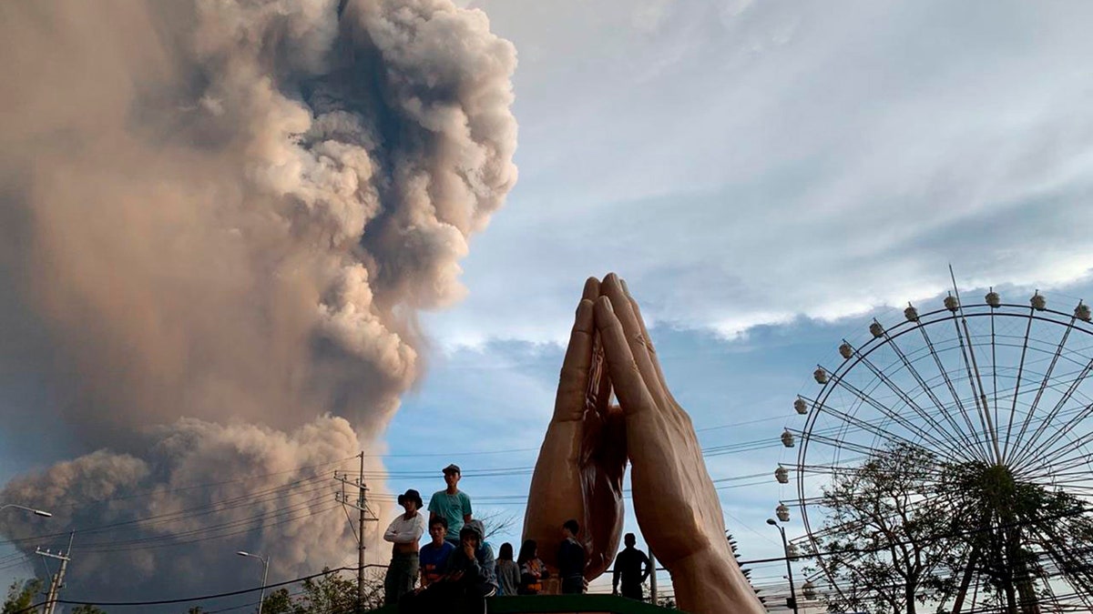 People watch as the Taal volcano spews ash and smoke during an eruption in Tagaytay, Cavite province south of Manila, Philippines on Sunday. Jan. 12, 2020.