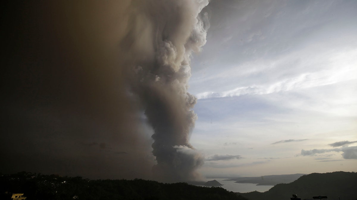 A tiny volcano near the Philippine capital that draws many tourists for its picturesque setting in a lake belched steam, ash and rocks in a huge plume Sunday, prompting thousands of residents to flee and officials to temporarily suspend flights.