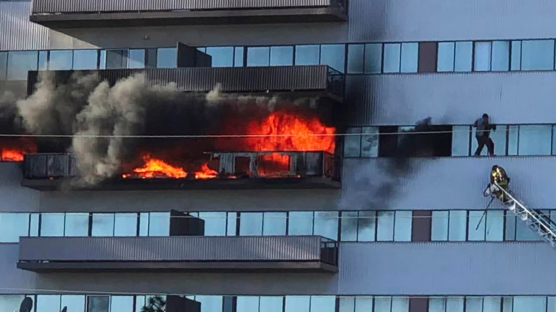 A Los Angeles Fire Department firefighter rescues a man who had climbed out on the side of a 25-story high-rise apartment, escaping flames from a burning apartment in Los Angeles, Jan. 29, 2020. 
