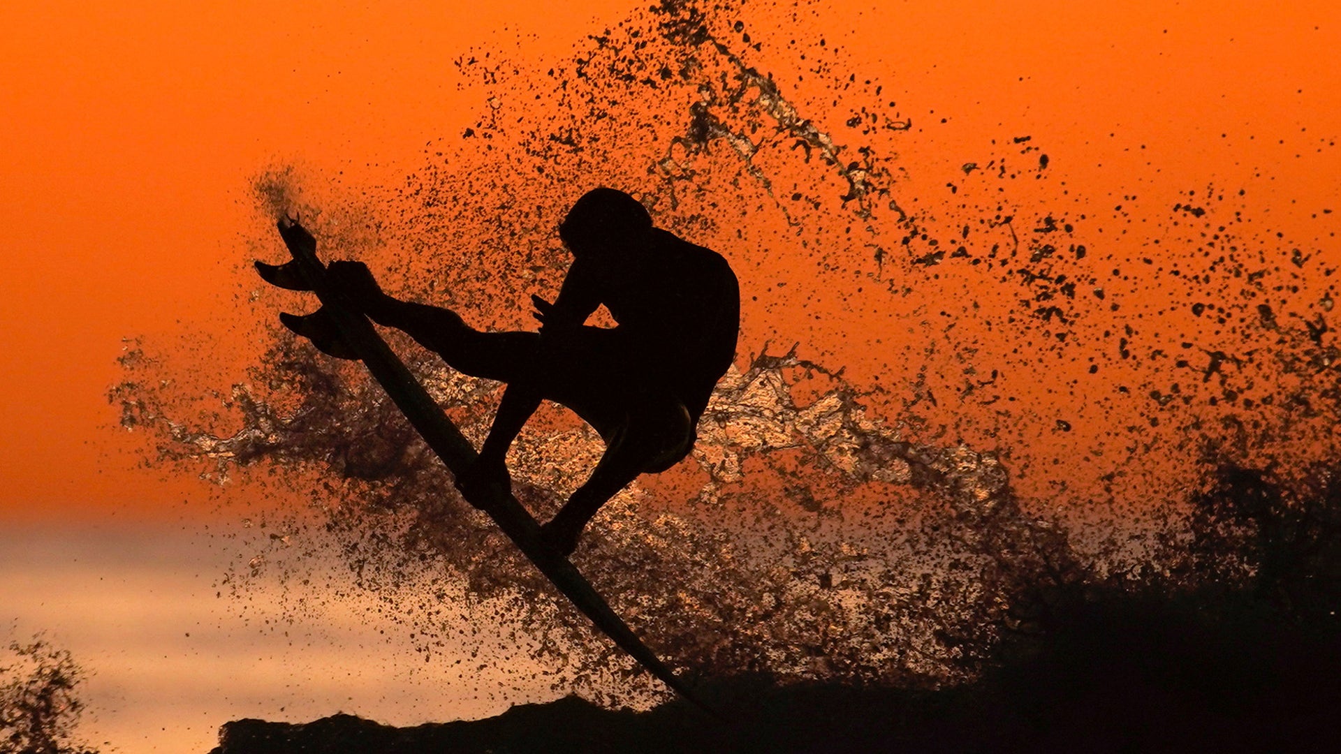 A surfer takes some air off a wave while surfing after sunset in Cardiff, California,  Jan. 7, 2020. 