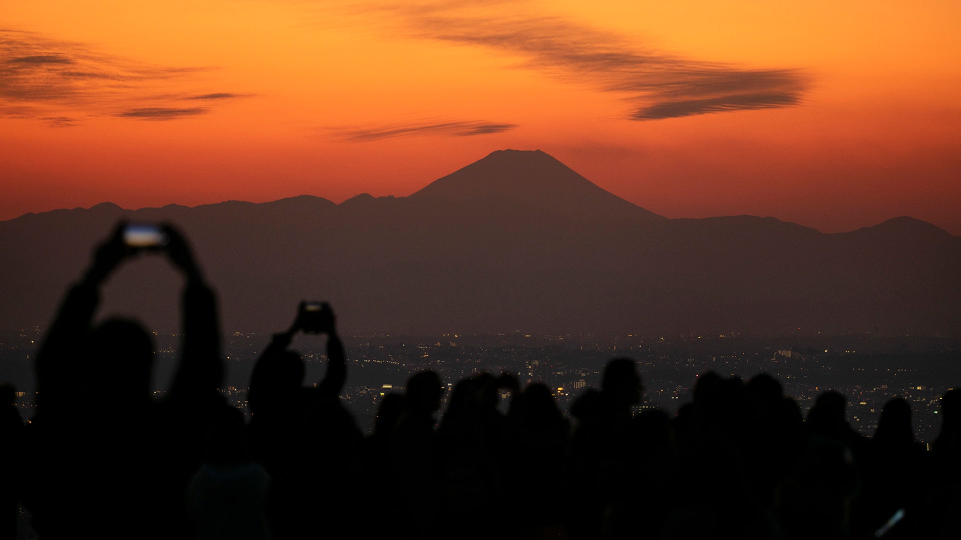 Visitors take pictures of Mount Fuji from the Shibuya Sky observation deck in Tokyo, Jan. 20, 2020.