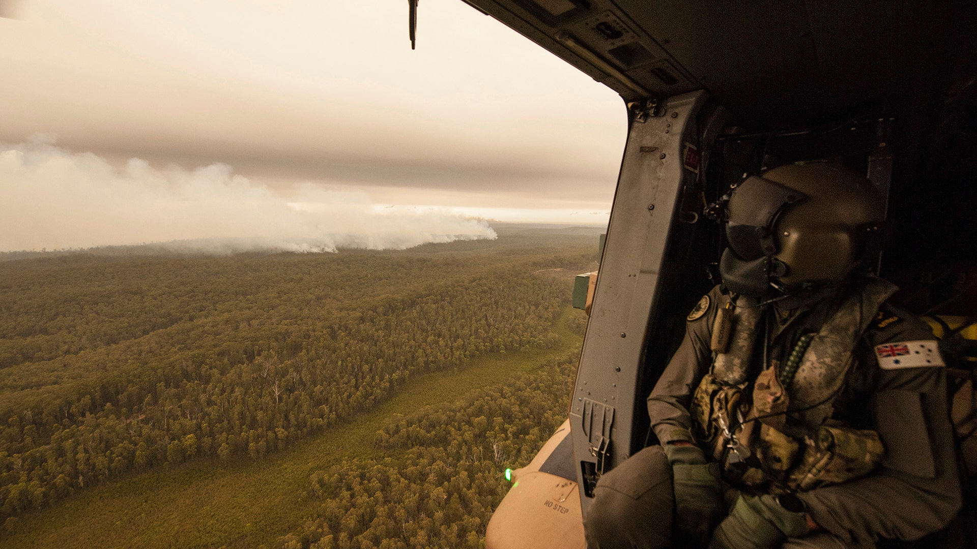 A Royal Australian Navy MRH-90 helicopter crew member looks out over fires burning near Cann River, Jan. 5, 2020.
