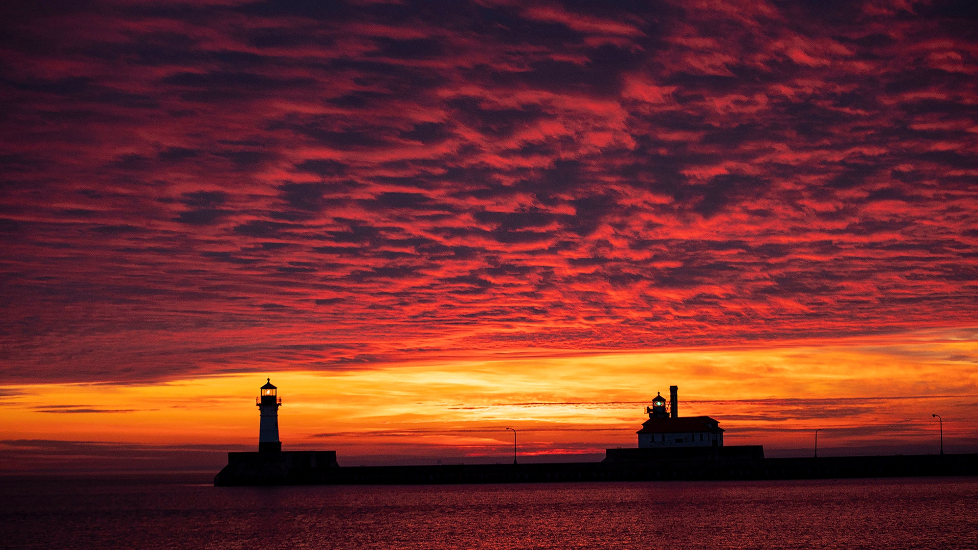 The first sunrise of 2020 brings deep orange and pink colors over the Duluth Harbor North and South Breakwater Lighthouses in Duluth, Minnesota, Jan. 1, 2020.