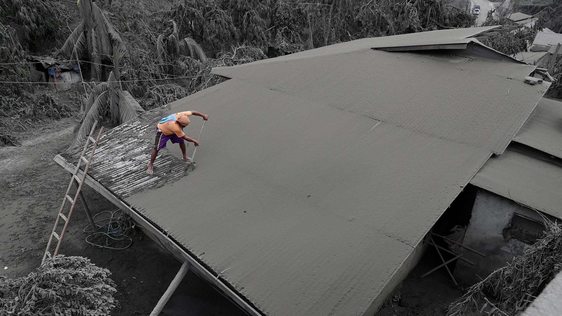A resident clears volcanic ash from his roof in Laurel, Philippines, Jan. 14, 2020. 