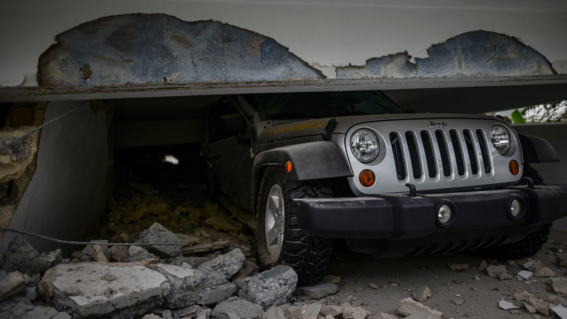 A car is crushed under a home that collapsed after the previous day's magnitude 6.4 earthquake in Yauco, Puerto Rico, Jan. 8, 2020. 
