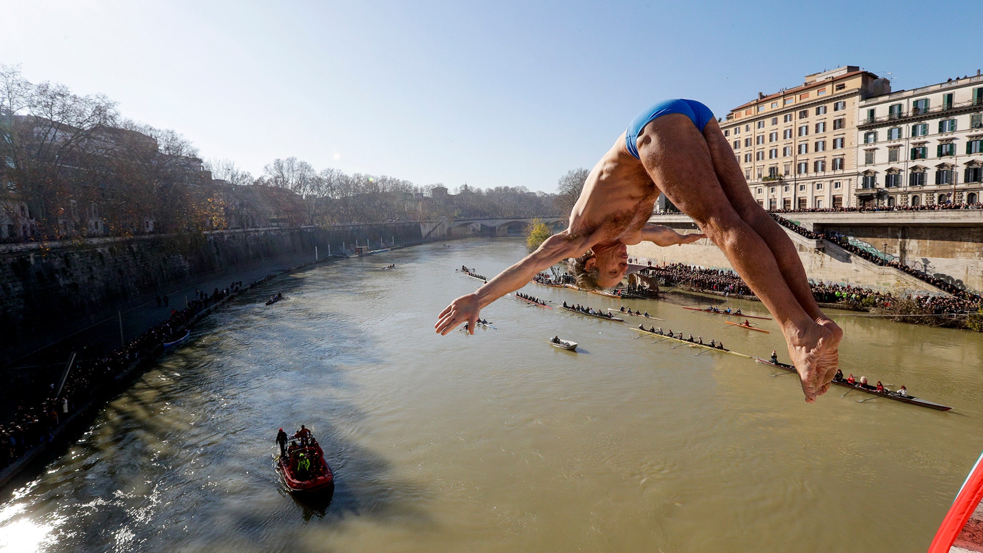 Marco Fois dives into the Tiber river from the 59 foot high Cavour Bridge in Rome, Jan. 1, 2020.