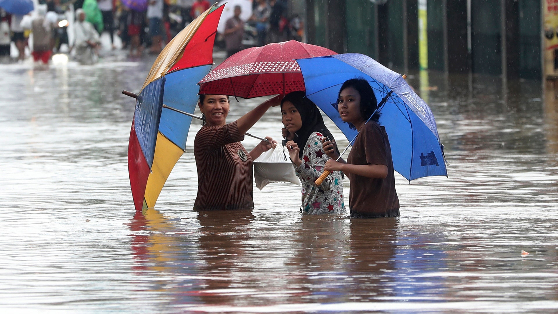 People wade through floodwaters at Jatibening on the outskirt of Jakarta, Indonesia, Jan. 1, 2020.