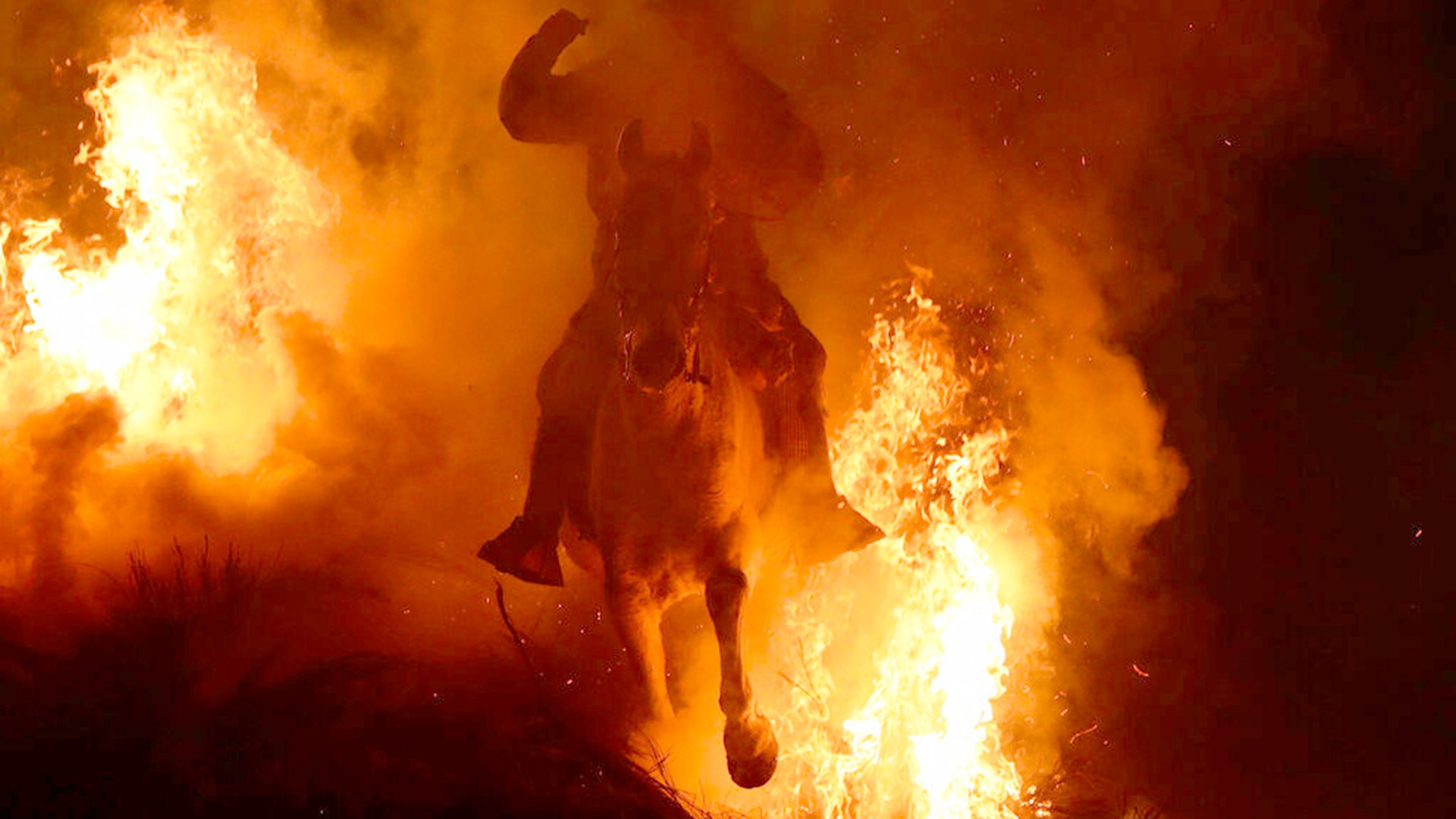 A man rides a horse through a bonfire as part of a ritual in honor of Saint Anthony the Abbot, the patron saint of domestic animals, in San Bartolome de Pinares, Spain, Jan. 16, 2020. 