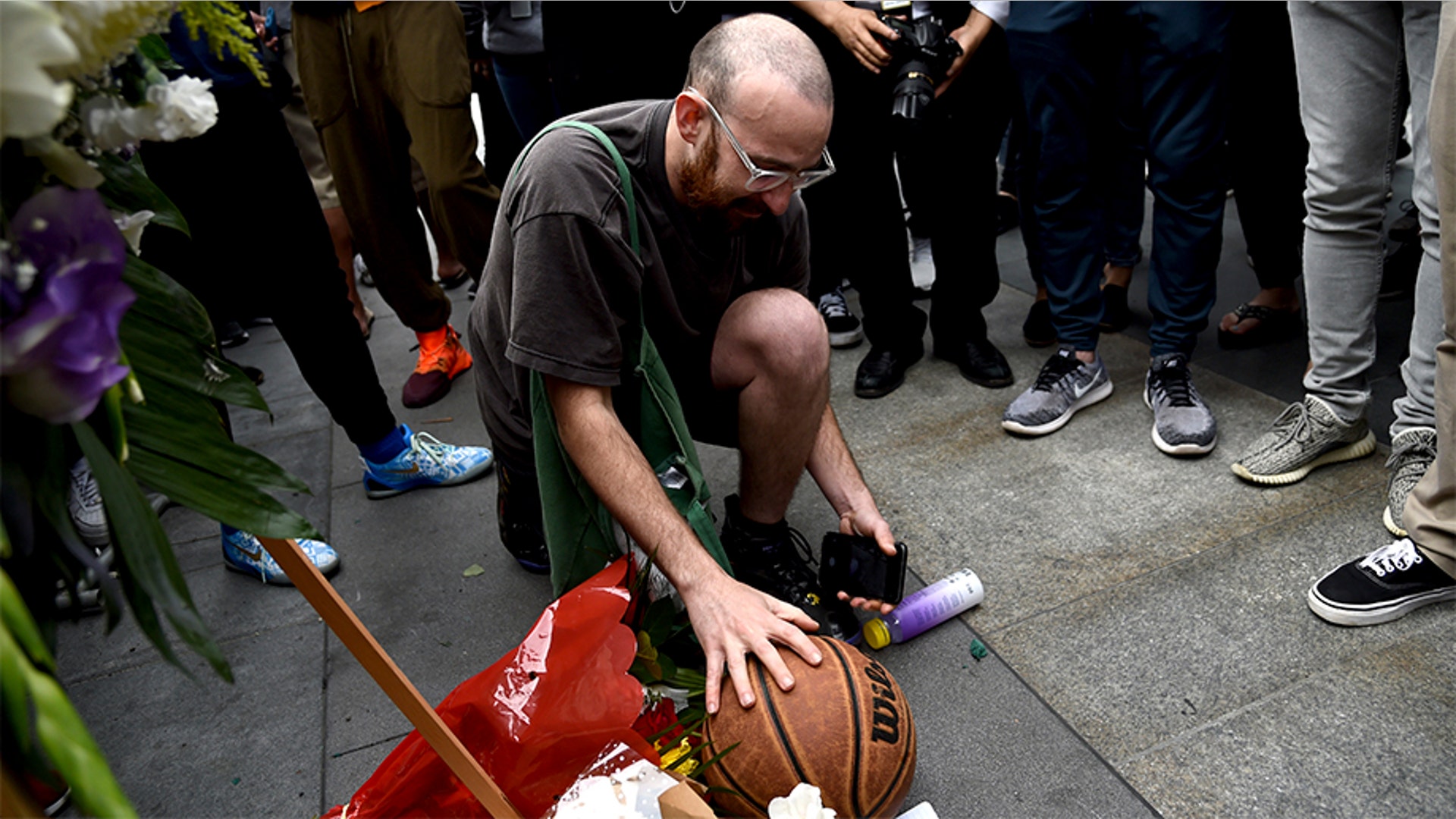 Newman Wolf places a basketball at a makeshift memorial for the late Kobe Bryant.
