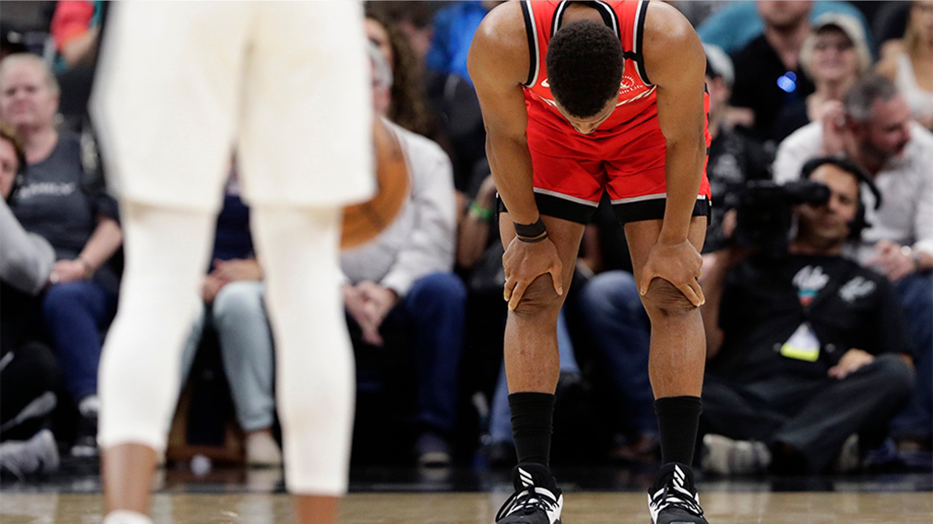 Toronto Raptors guard Kyle Lowry (7) holds his head down as players stop the action of a basketball game during the first half against the San Antonio Spurs. 