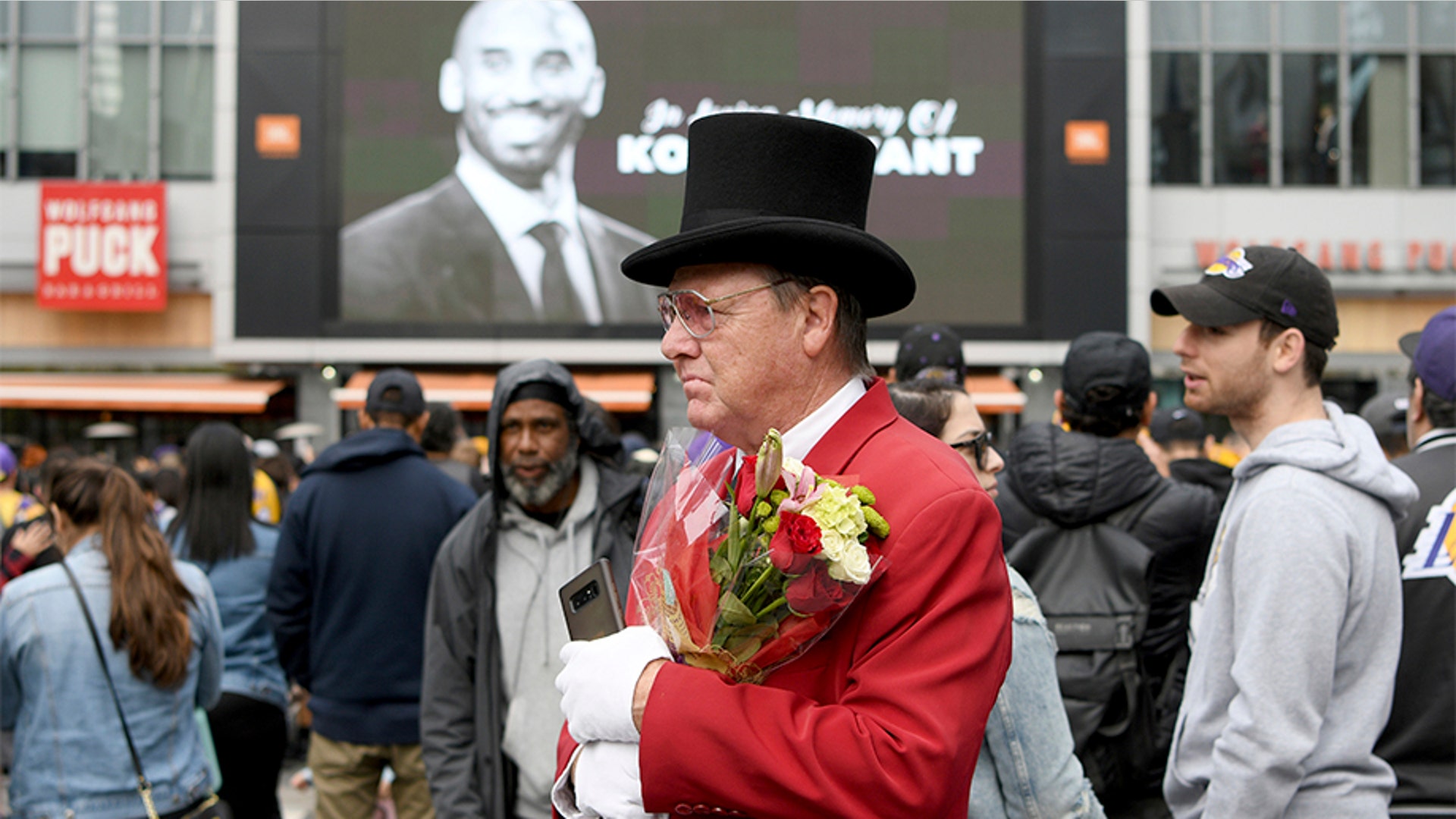 Gregg Donovan, AKA The Hollywood Ambassador, carries flowers at a gathering for Kobe Bryant near Staples Center in Los Angeles.