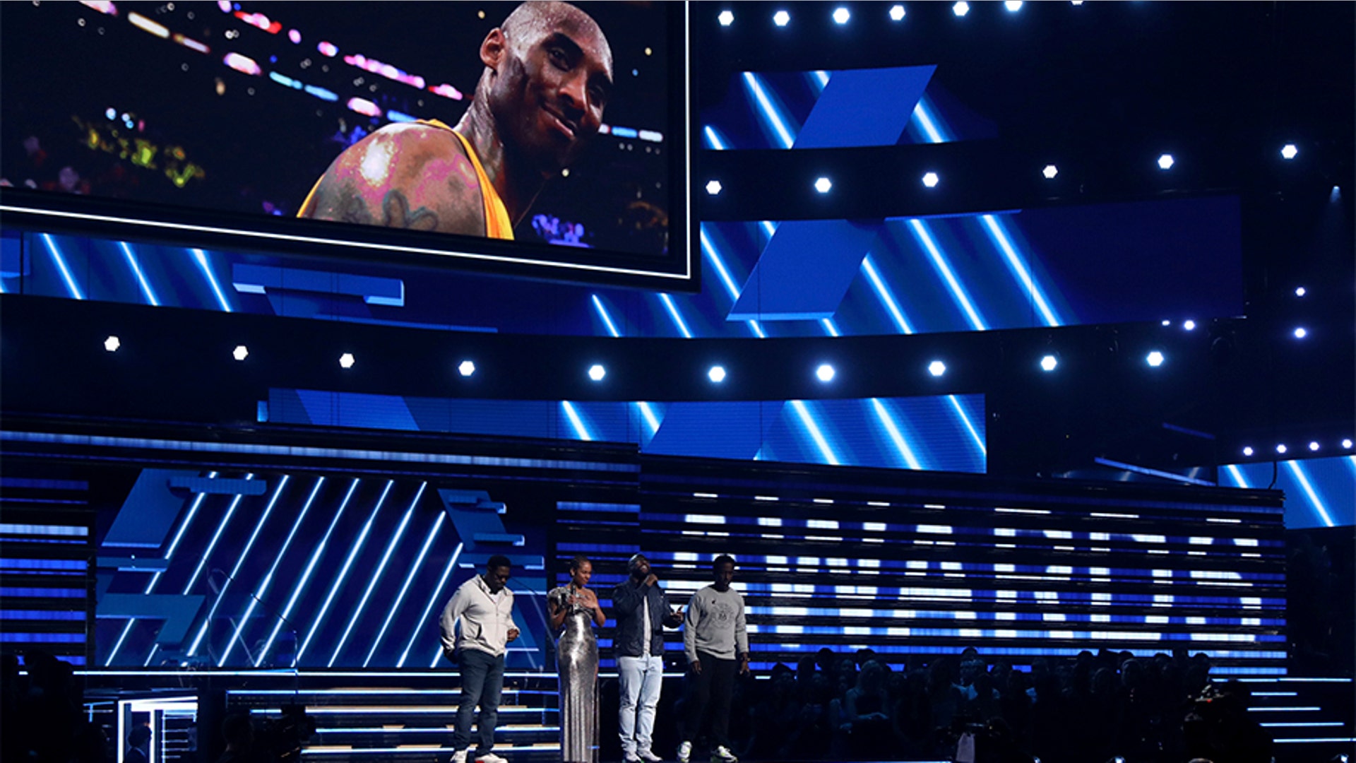 Nathan Morris, from left, Wanya Morris, Shawn Stockman, of Boyz II Men‎, and Alicia Keys, second left, sing a tribute in honor of the late Kobe Bryant, seen on screen, at the 62nd annual Grammy Awards in Los Angeles. 