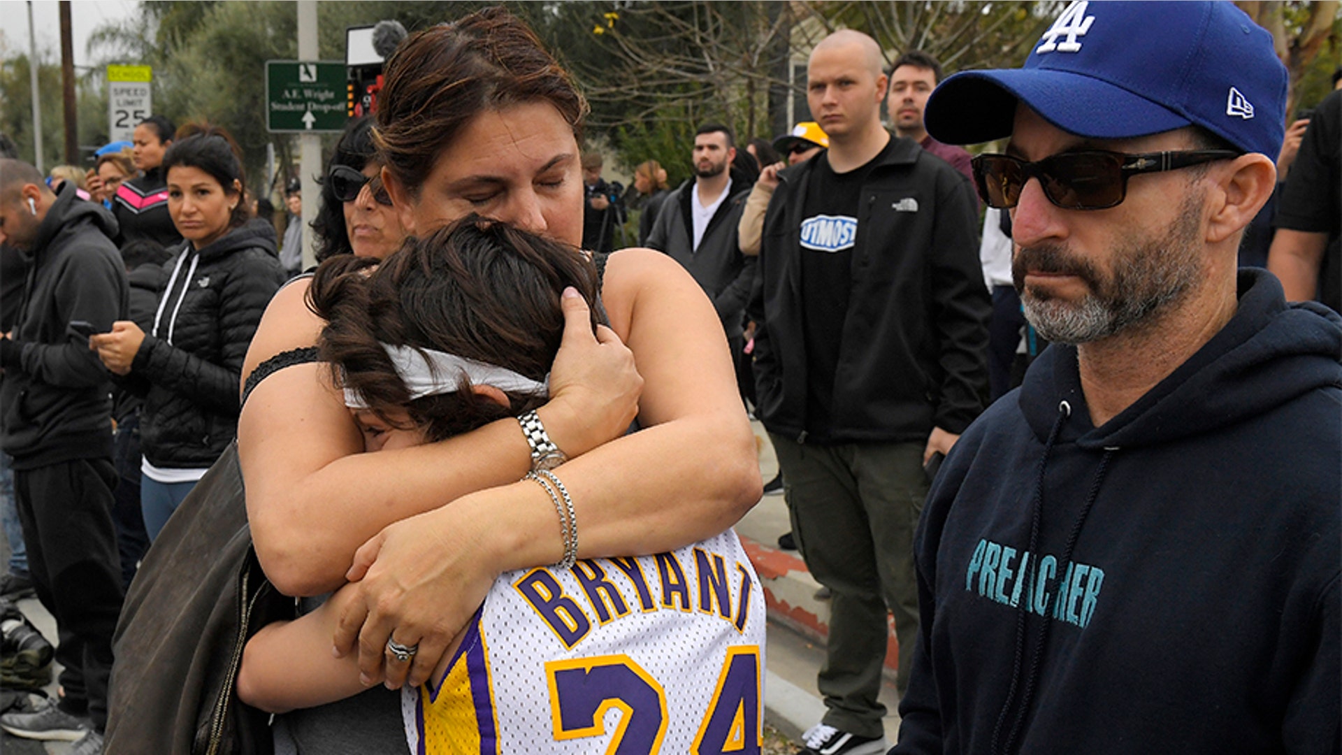 Elana Hirschman, left, hugs her son Bryan, 11, as her husband Craig stands by at the scene of a helicopter crash Bryant and as many as eight others.