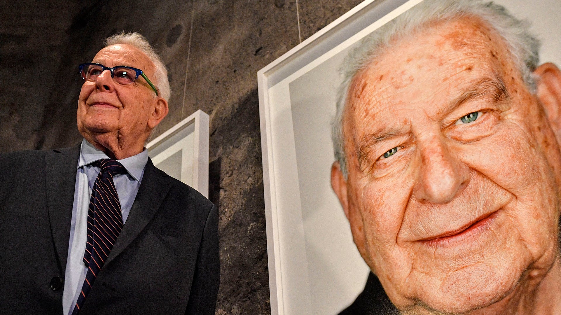 Holocaust survivor Naftali Furst stands next to his portrait during the opening of the exhibition 'Survivors - Faces of Life after the Holocaust' at the former coal mine Zollverein in Essen, Germany, on Jan. 21, 2020. 