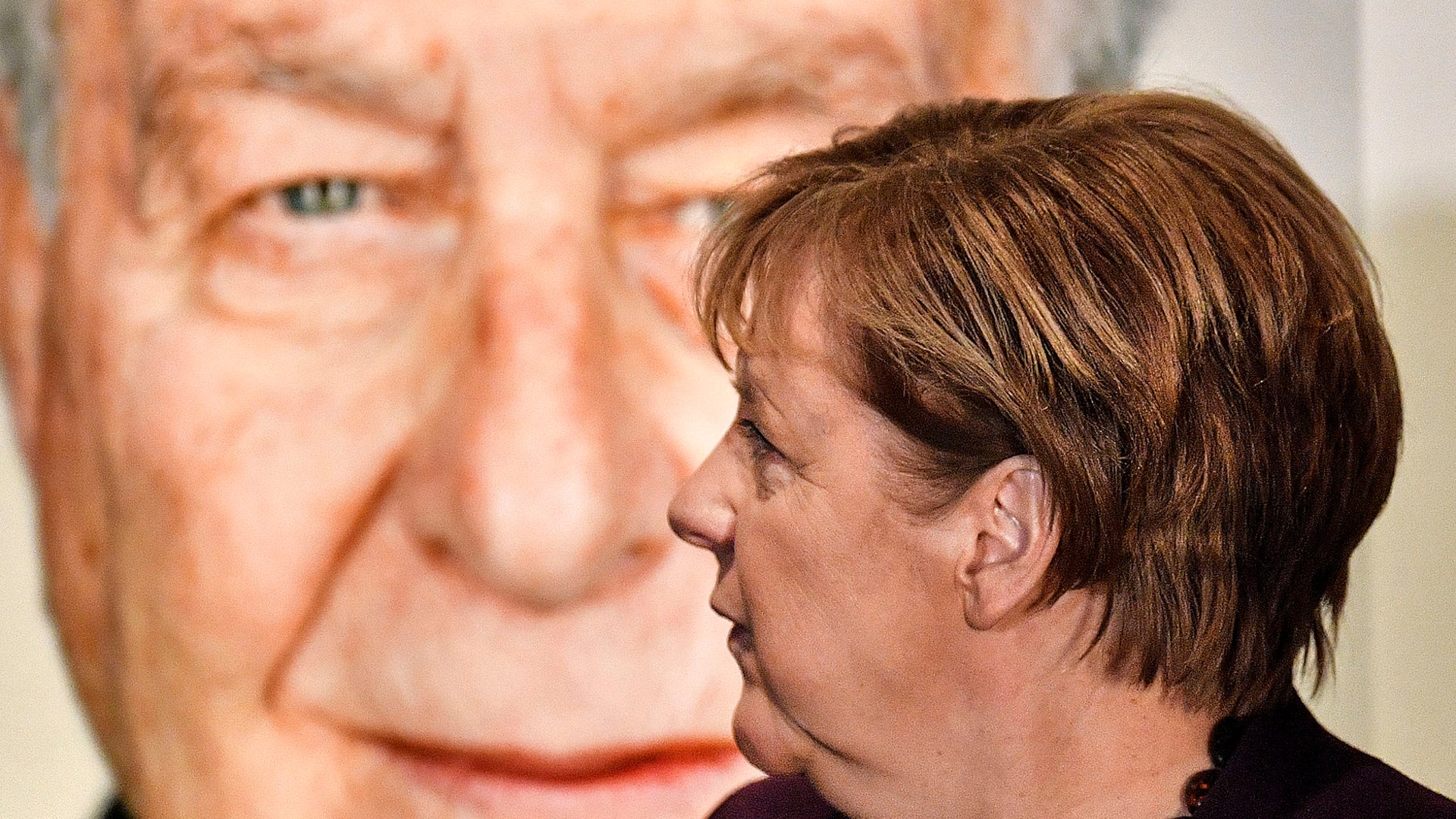 German chancellor Angela Merkel stands in front of a portrait of Holocaust survivor Naftali Furst during the opening of the exhibition "Survivors - Faces of Life after the Holocaust" at the former coal mine Zollverein in Essen, Germany, on Jan. 21, 2020. The industrial world heritage landmark Zollverein is showing an exhibition of 75 portraits of Jewish survivors, photographed in Israel by German artist Martin Schoeller.