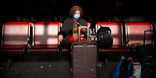 A traveler wears a face mask as she sits in a waiting room at Beijing West Railway Station in Beijing.