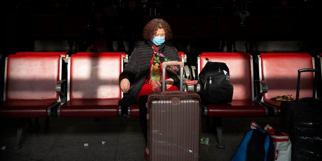 A traveler wears a face mask as she sits in a waiting room at Beijing West Railway Station in Beijing.