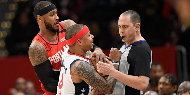 Washington Wizards guard Isaiah Thomas (4) comes in contact with referee Marat Kogut, right, next to Portland Trail Blazers forward Carmelo Anthony, back, during the first half of an NBA basketball game, Friday, Jan. 3, 2020, in Washington. Thomas was ejected from the game. (Associated Press)