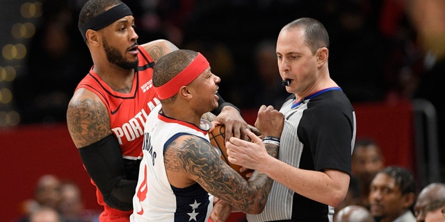 Washington Wizards guard Isaiah Thomas (4) comes in contact with referee Marat Kogut, right, next to Portland Trail Blazers forward Carmelo Anthony, back, during the first half of an NBA basketball game, Friday, Jan. 3, 2020, in Washington. Thomas was ejected from the game. (Associated Press)